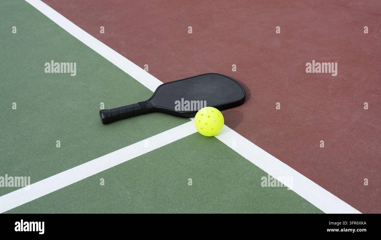 Una racchetta e una palla da pickleball su un campo da pickleball Foto Stock