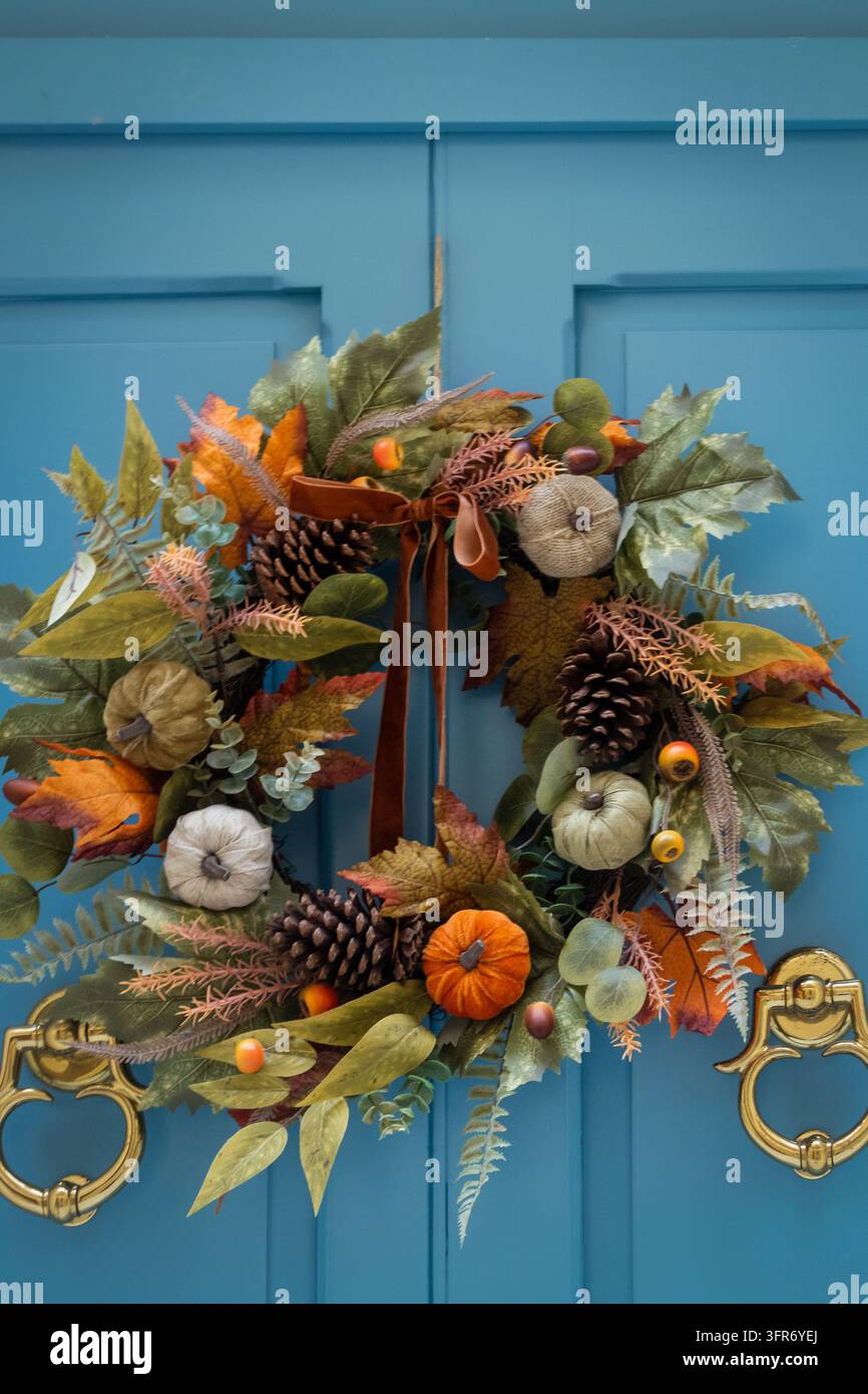 Ghirlanda autunnale con zucche e pigne appesa a una porta d'ingresso blu per la decorazione autunnale Foto Stock