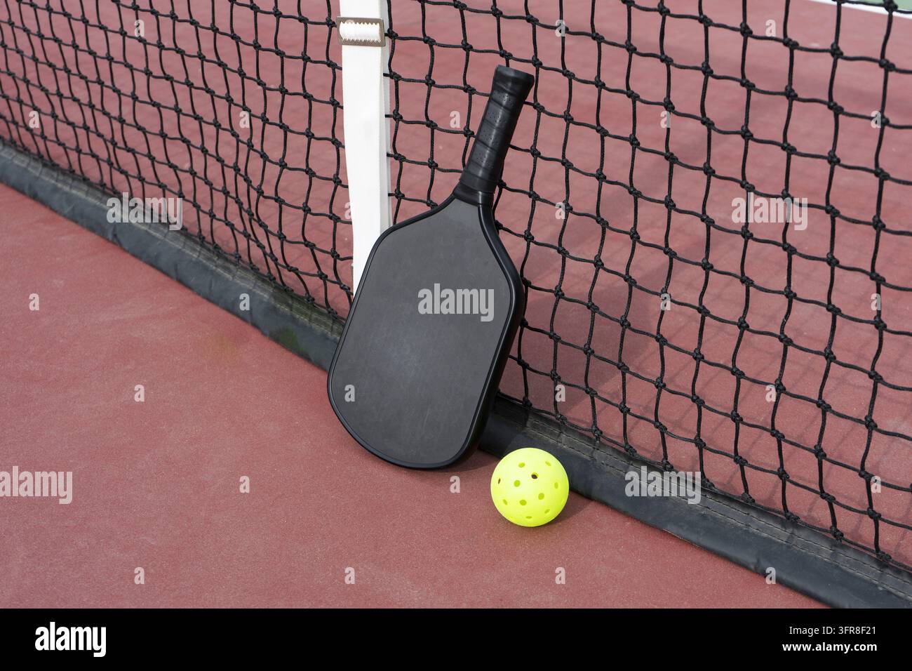 Una racchetta e una palla da pickleball nella rete sul campo da pickleball Foto Stock