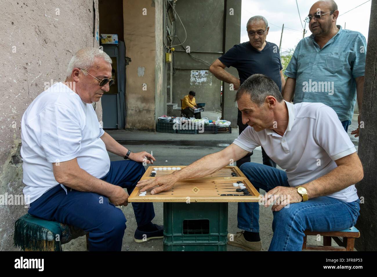 Uomini che giocano a backgammon su un tavolo di legno allestito in strada mentre altri osservano, Yerevan, Yerevan, Armenia Foto Stock