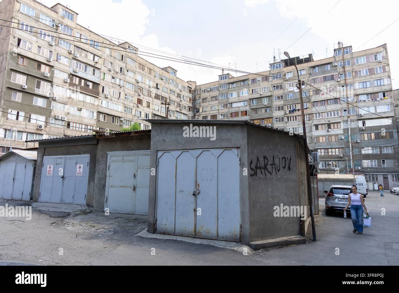 Filiera di garage metallici con graffiti in un cortile con palazzi di appartamenti sovietici sullo sfondo, Yerevan, Yerevan, Armenia Foto Stock