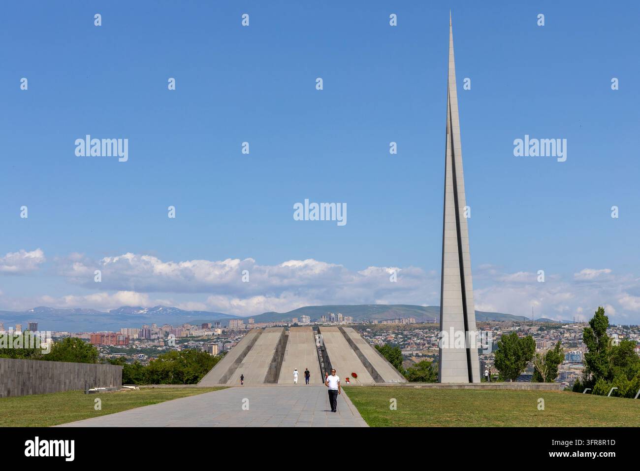 Alto spire di pietra che si innalza accanto alla struttura piramidale a gradini del complesso memoriale del Genocidio Armeno di Tsitsernakaberd, Yerevan, Yerevan, Armenia Foto Stock