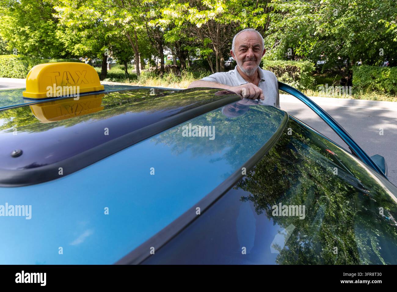 Autista di taxi appoggiato sul tetto della sua auto con un cartello giallo da taxi, provincia di Shirak, Gyumri, Armenia Foto Stock