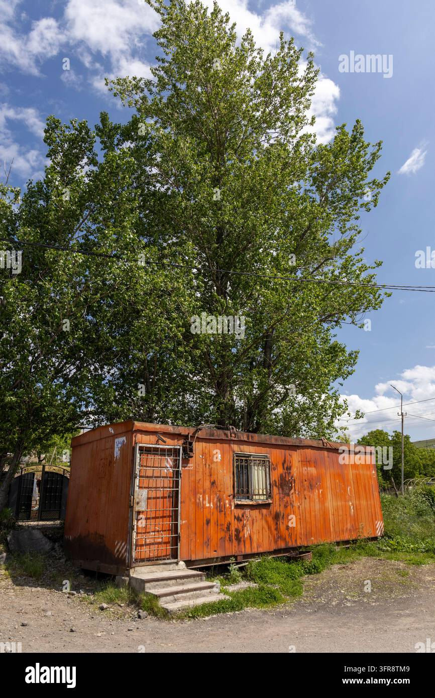 Vecchia cabina di metallo arrugginita con una porta sbarrata che si trova sotto un grande albero, provincia di Gegharkunik, Sevan, Armenia Foto Stock