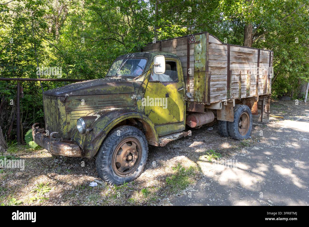 Vecchio camion arrugginito dell'era sovietica con un cassone in legno abbandonato tra gli alberi, provincia di Gegharkunik, Sevan, Armenia Foto Stock