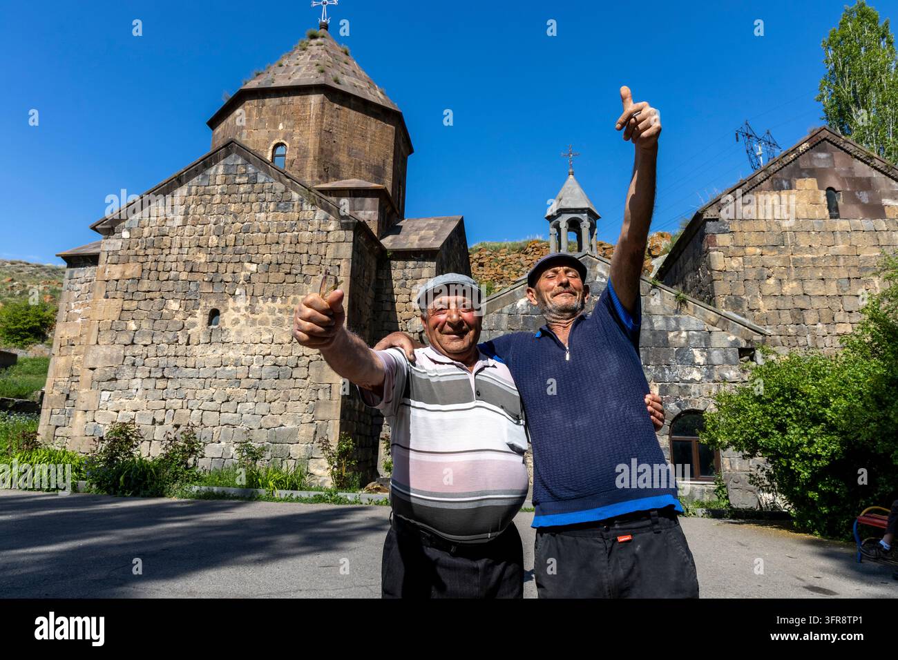Due uomini allegri che fanno il pollice alzato davanti agli edifici in pietra del monastero di Vanevan, provincia di Gegharkunik, Artsvanist, Armenia Foto Stock