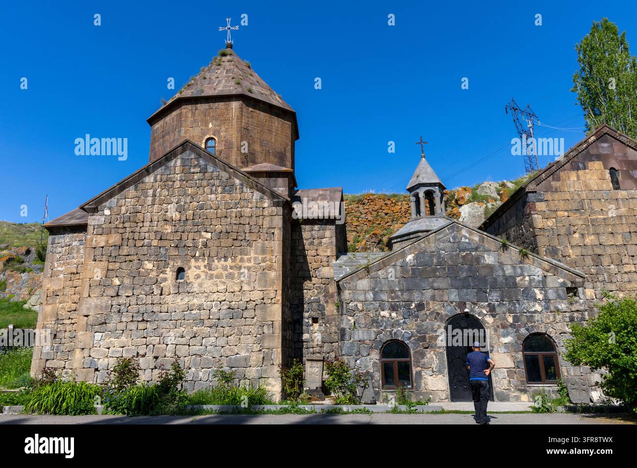 Uomo che si avvicina all'ingresso ad arco del monastero di Vanevan circondato da edifici in pietra, provincia di Gegharkunik, Artsvanist, Armenia Foto Stock