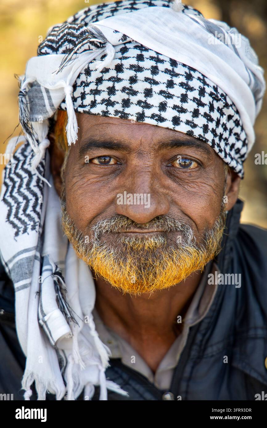 Un uomo anziano con una barba tinta di arancione indossa un foulard a scacchi bianchi e neri in un ritratto ravvicinato, Gujarat, Mandvi, India Foto Stock