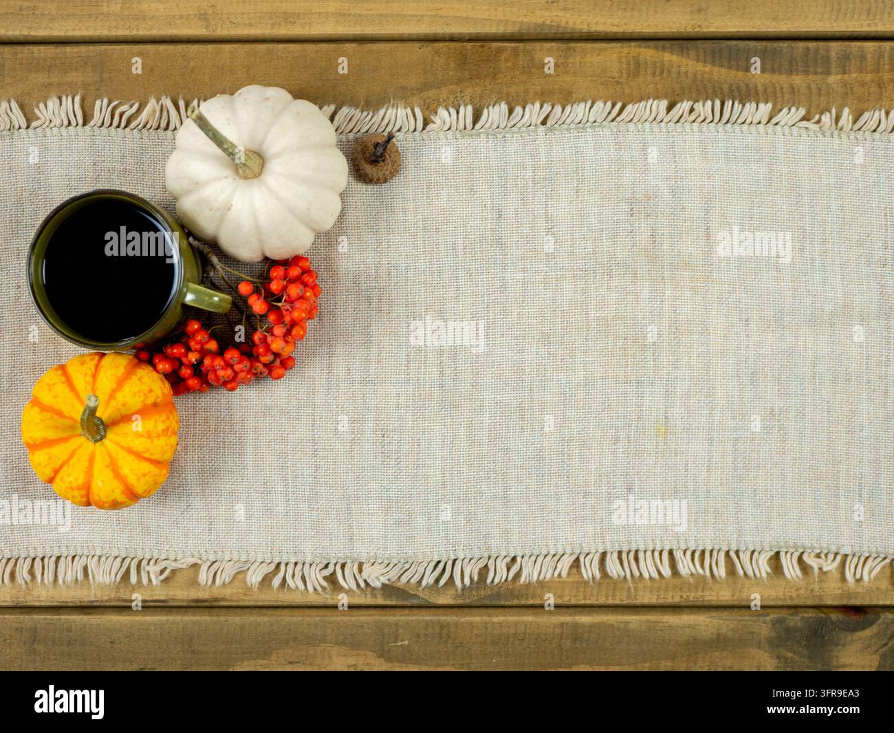 Sfondo autunnale con tazza di caffè, zucche bianche e arancioni su tessuto di lino, atmosfera accogliente autunnale con ampio spazio per testo e design Foto Stock