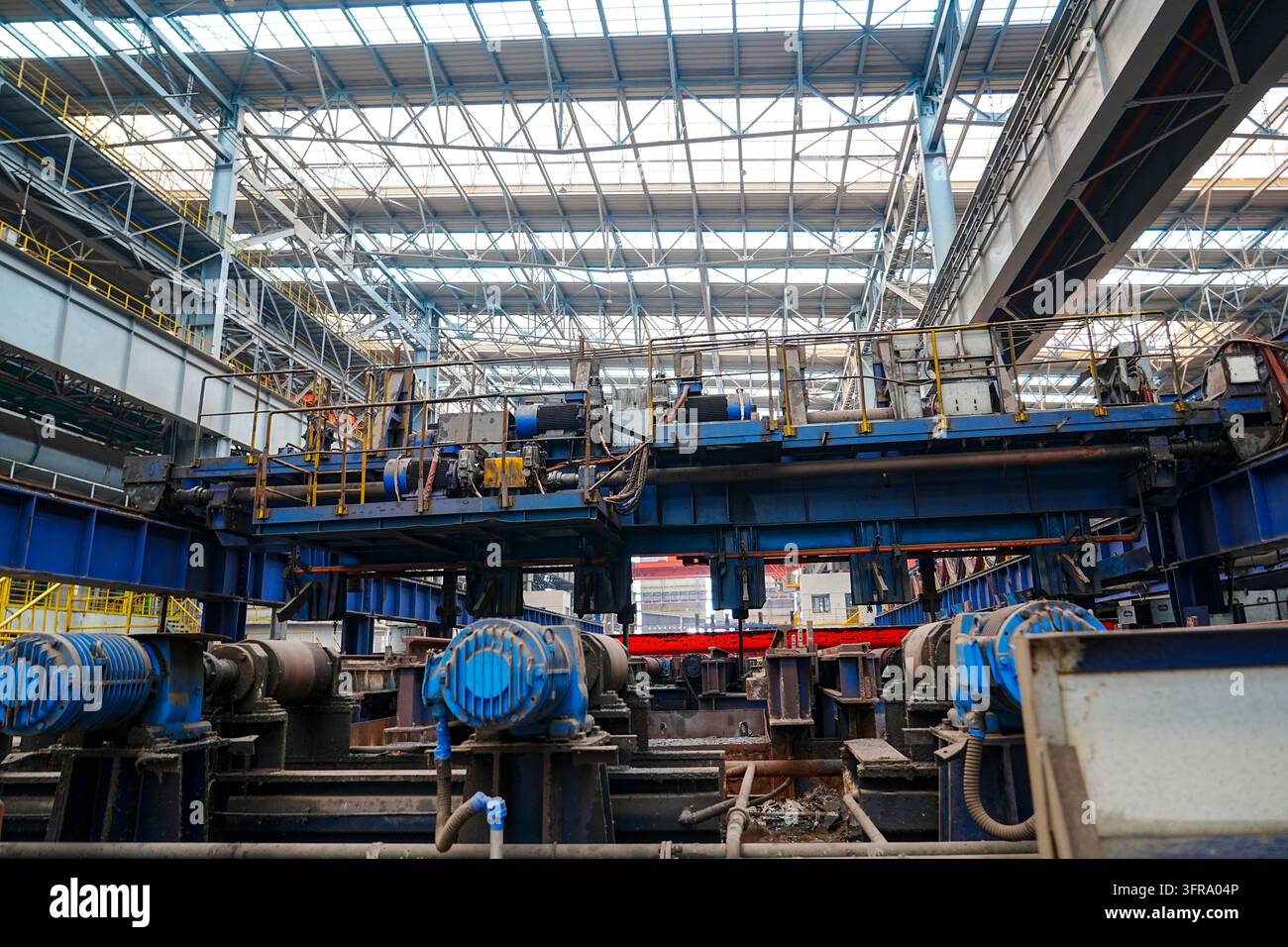 Nell'officina di laminazione a caldo di un'azienda siderurgica di medie dimensioni all'interno dell'impianto siderurgico, le billette di acciaio caldo rosso brillante vengono laminate attraverso il rotolo Foto Stock