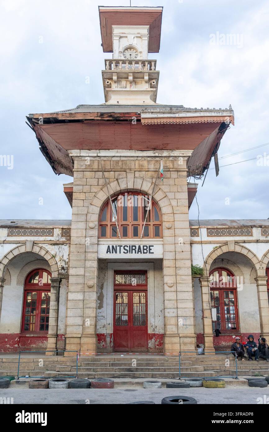 Torre dell'orologio ornata che si innalza sopra l'ingresso ad arco della vecchia stazione ferroviaria di Antsirabe con una bandiera malgascia montata sotto il tetto, Vakinankaratra, Foto Stock
