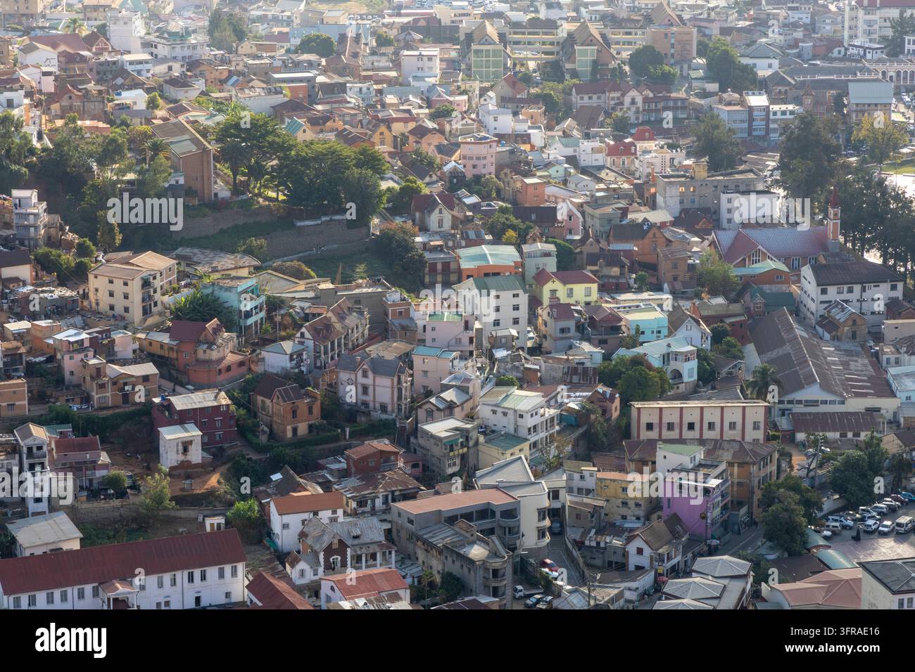 Uomini riuniti accanto a moto parcheggiate e a un taxi su una strada collinare colorata, Analamanga, Antananarivo, Madagascar Foto Stock