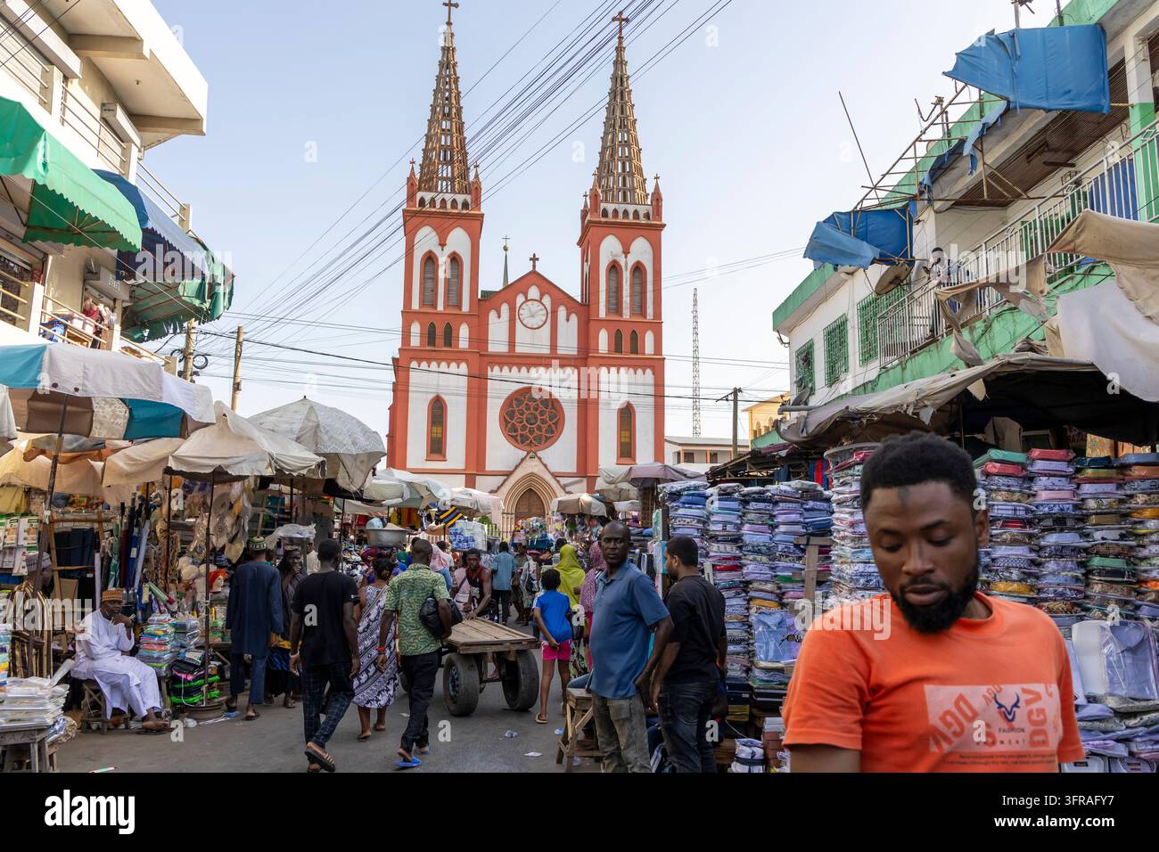 Bancarelle di mercato affollate sistemate davanti a una cattedrale con due campanili nel centro città, Regione Marittima, Lomé, Togo Foto Stock