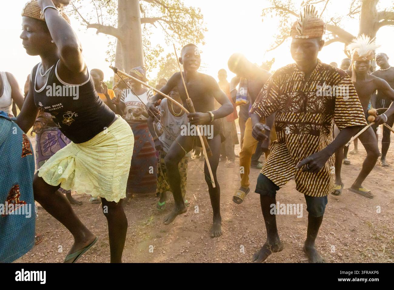Tribù Tamberma che esegue una danza tradizionale con arco e frecce al tramonto in un bosco di baobab, Koutammakou, Tamberma, Togo Foto Stock