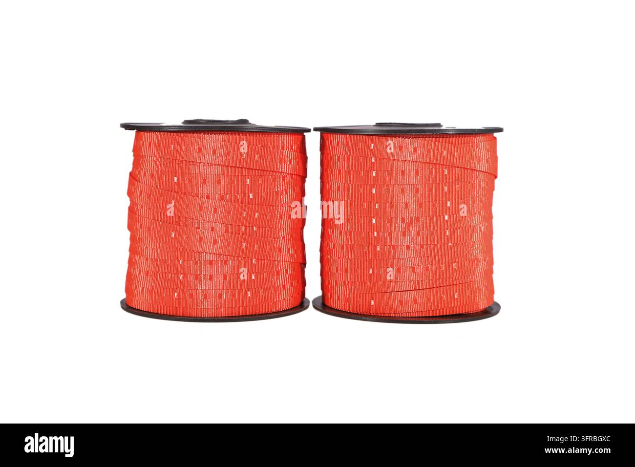 Due rotoli di nastro per confezioni regalo arancione brillante con fori uniformemente distanziati, ordinatamente posizionati fianco a fianco su uno sfondo bianco semplice. Sono comunemente u Foto Stock