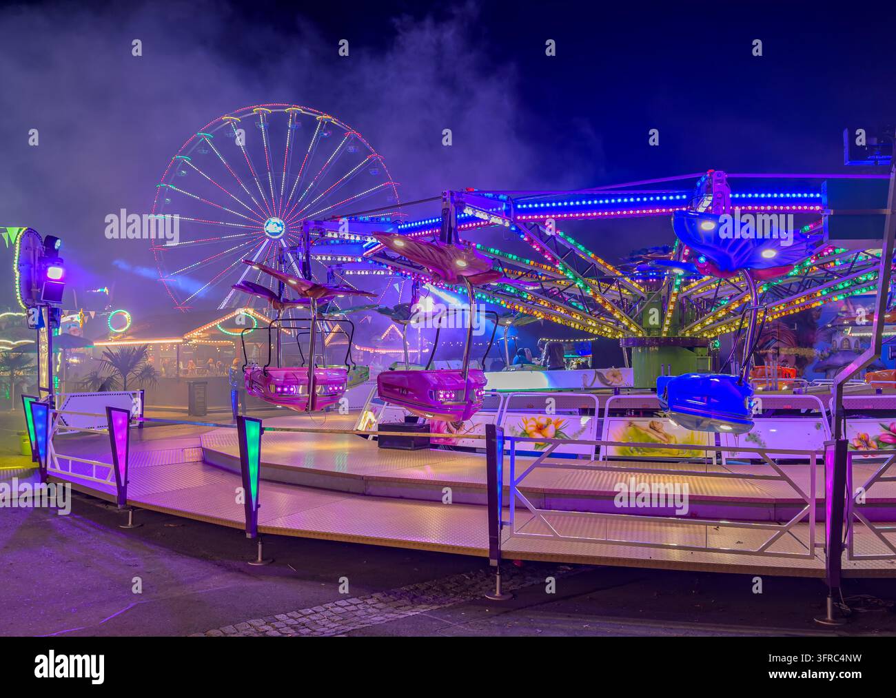 Una ruota panoramica luminosa a un festival autunnale notturno in città. Luci colorate creano un'atmosfera festosa mentre l'attrazione stan Foto Stock