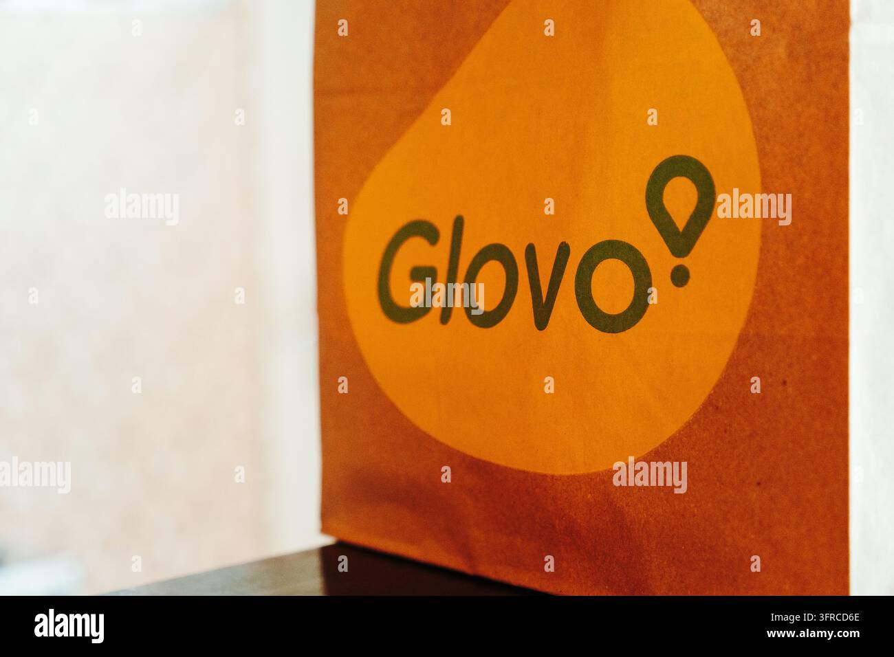 Novi Sad, Serbia - 9 settembre 2026. Una borsa di consegna in carta del marchio Glovo è esposta al chiuso, rappresentando gli ordini di cibo online, i servizi di consegna a Foto Stock