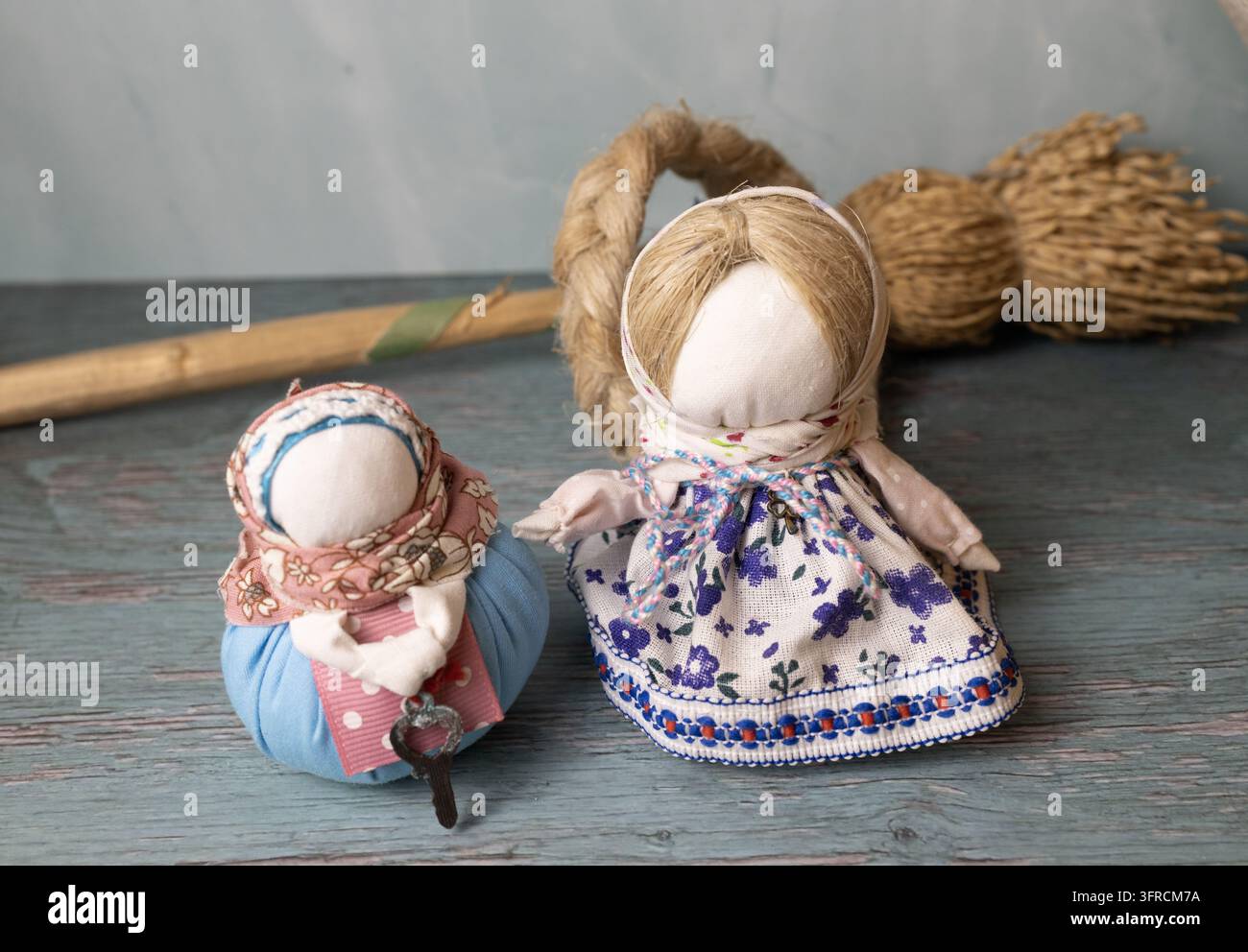 Bambole Motanka ucraine tradizionali in abiti folkloristici ricamati con grano su un tavolo di legno rustico Foto Stock