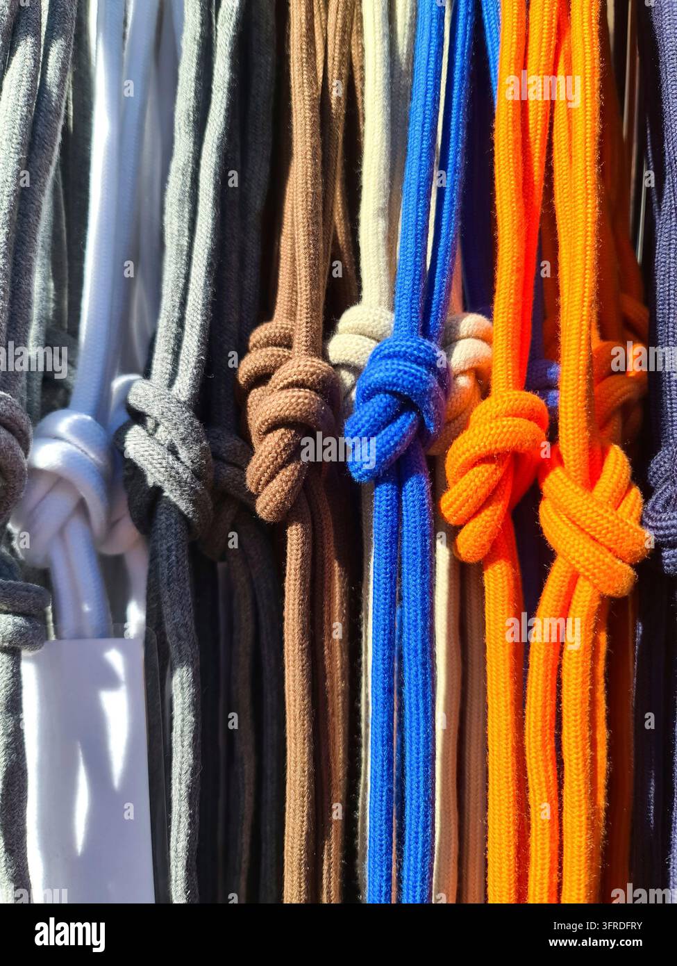File di disegni colorati appesi verticalmente, che mostrano varie tonalità e estremità annodate Tessuto con texture che crea motivi Foto Stock