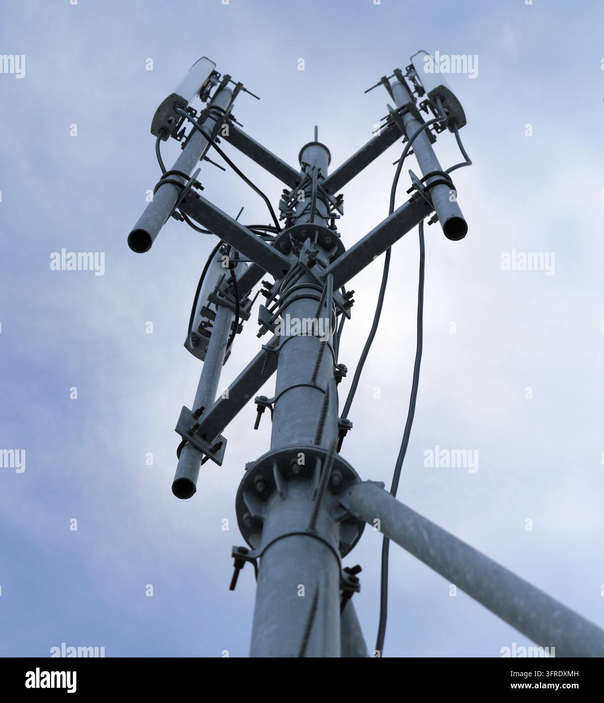Torre cellulare che si erge in un cielo luminoso, antenne e parabole che supportano reti 5G e senza fili, consentendo connettività mobile, trasmissione dati e modalità Foto Stock