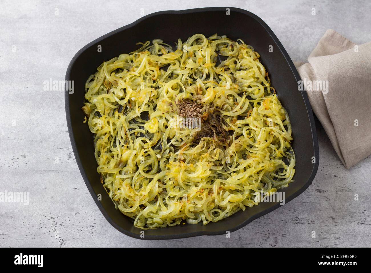 Padella antiaderente con cipolle fritte e spezie: cumino e pepe nero, vista dall'alto. Preparazione del piatto tradizionale mediorientale mujadara Foto Stock