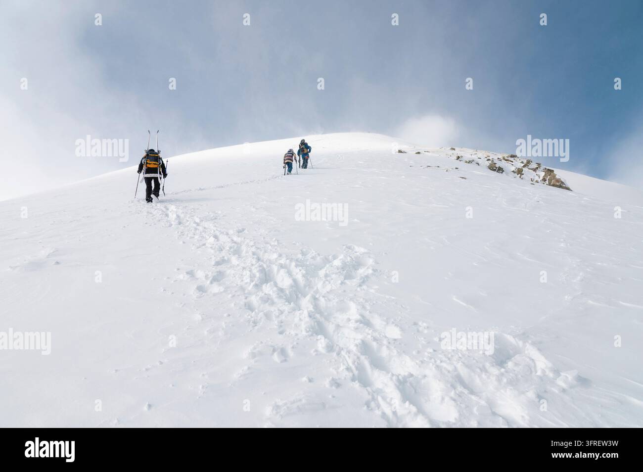Alpinisti che camminano lungo una cresta innevata con gli sci nello zaino. Sci sulla pista di salita per discesa in freeride. Sciatori di backcountry. sci f Foto Stock