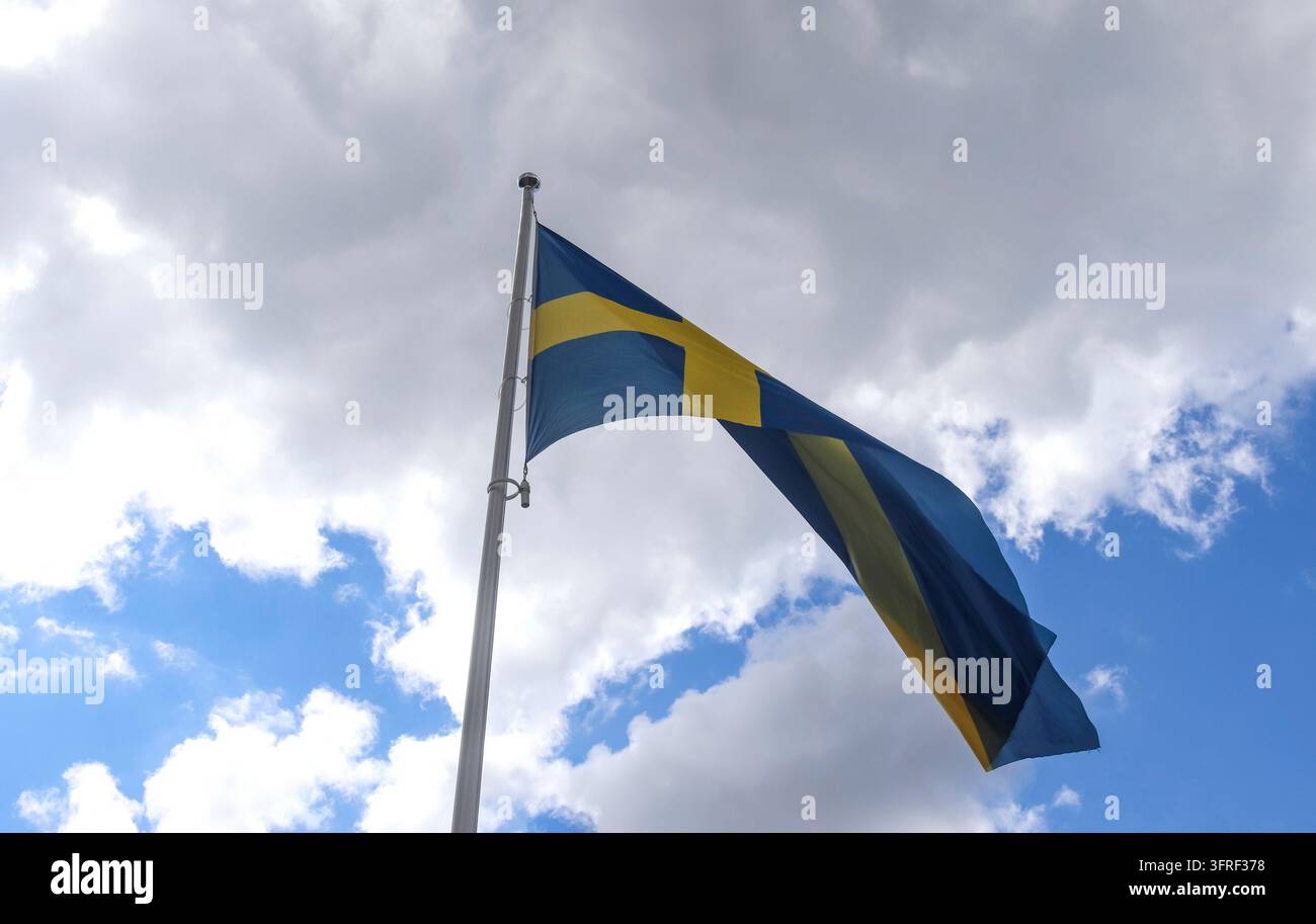Bandiera della Svezia su un'asta che si muove lentamente nel vento contro il cielo Foto Stock