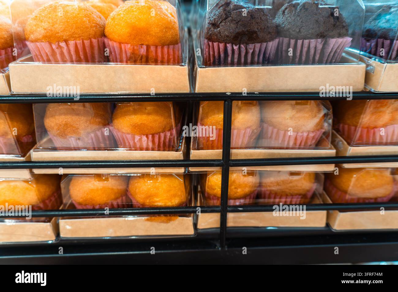 Muffin in stampi di carta si trovano dietro una vetrina di panetteria a Da Lat, Vietnam. Foto Stock
