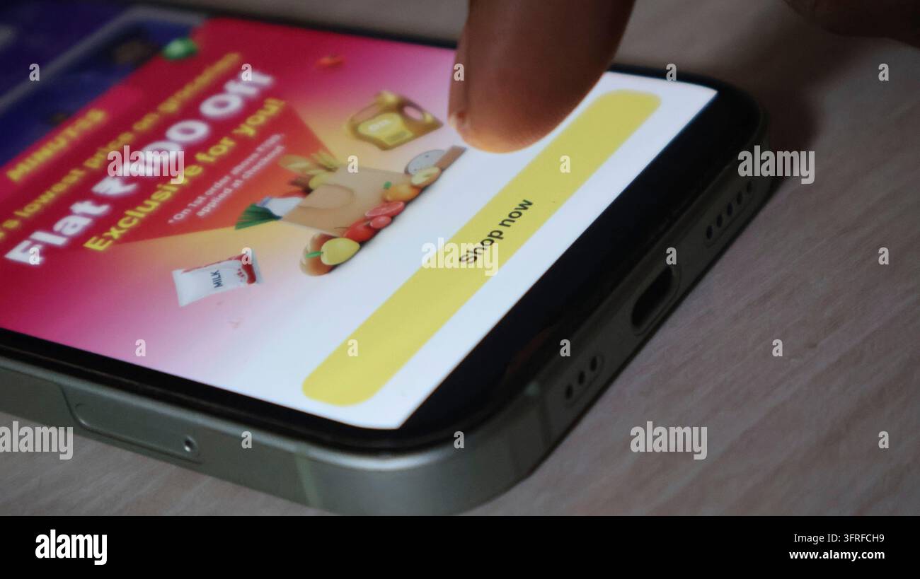 Vista ravvicinata di un dito che tocca un pulsante giallo di un'applicazione mobile su uno schermo touch. Campagna di marketing digitale con uno sconto sugli acquisti di generi alimentari su moder Foto Stock
