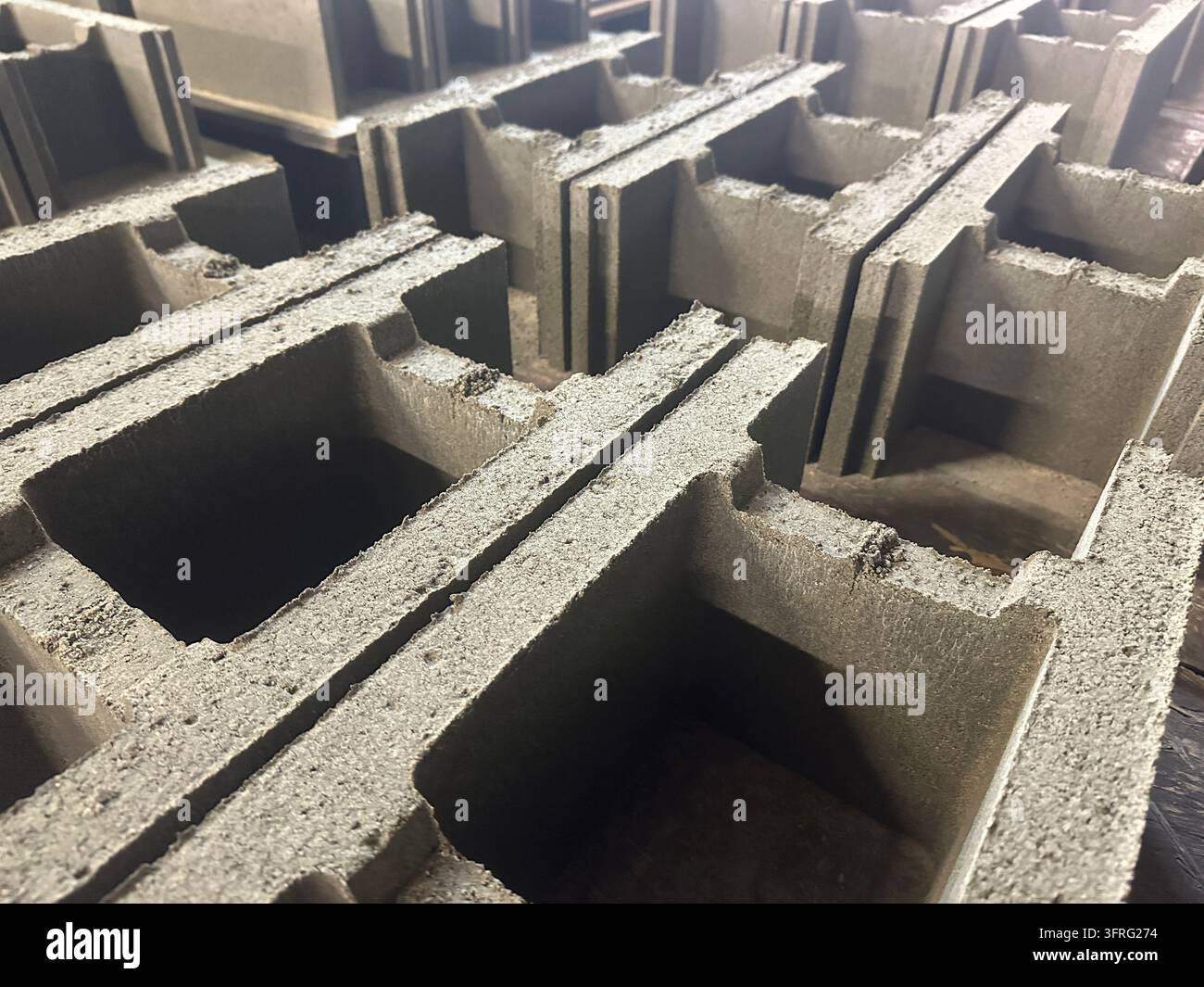 Pila di blocchi di muratura cavi in cemento grigio prodotti per la costruzione edilizia. Foto Stock