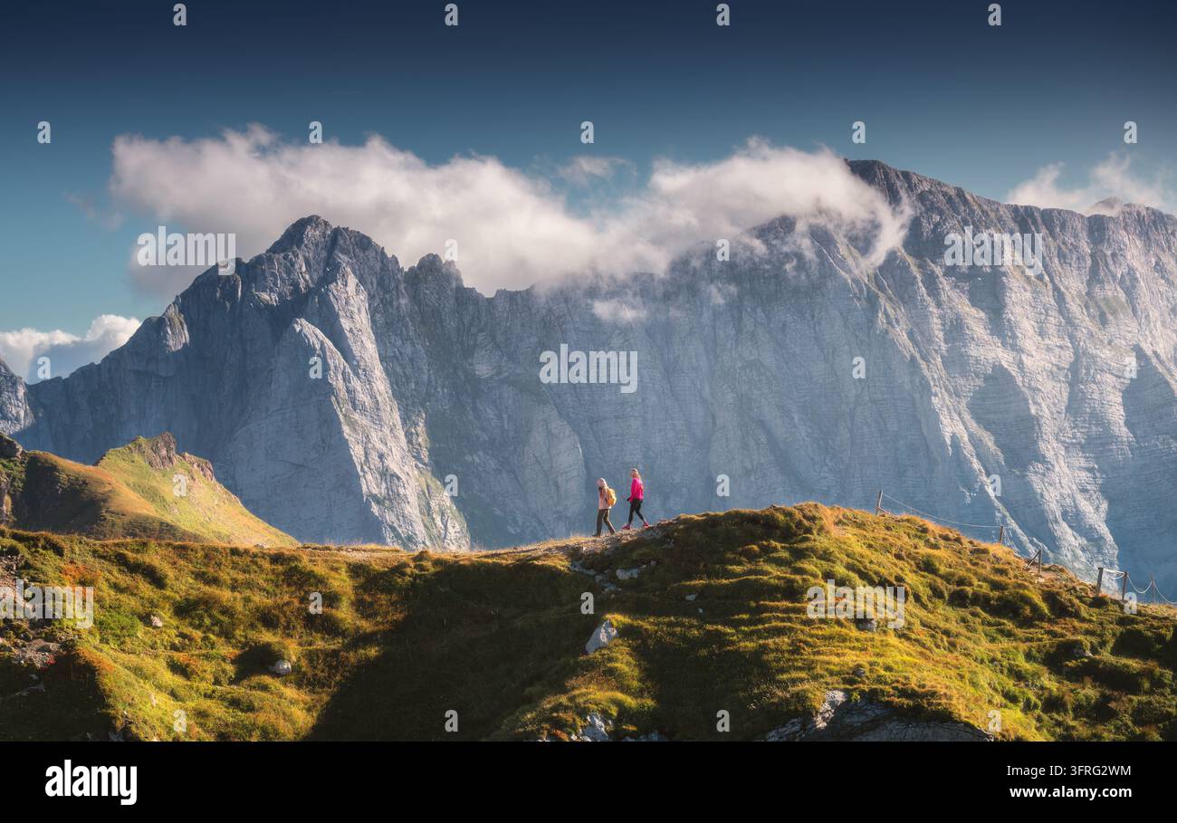 Due escursionisti che camminano lungo una cresta montuosa erbosa, picchi rocciosi Foto Stock