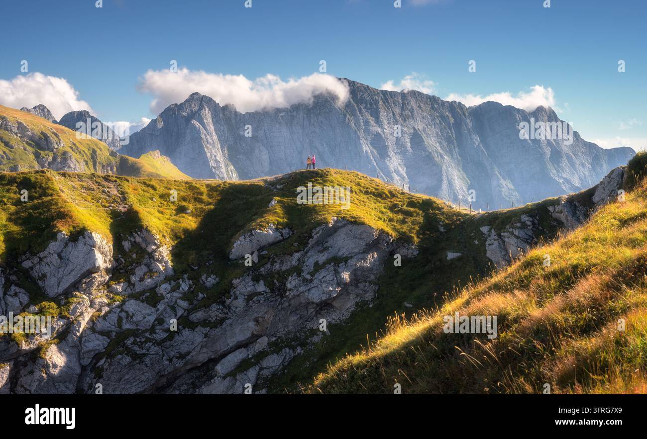 Due escursionisti che camminano lungo una cresta montuosa erbosa, picchi rocciosi Foto Stock