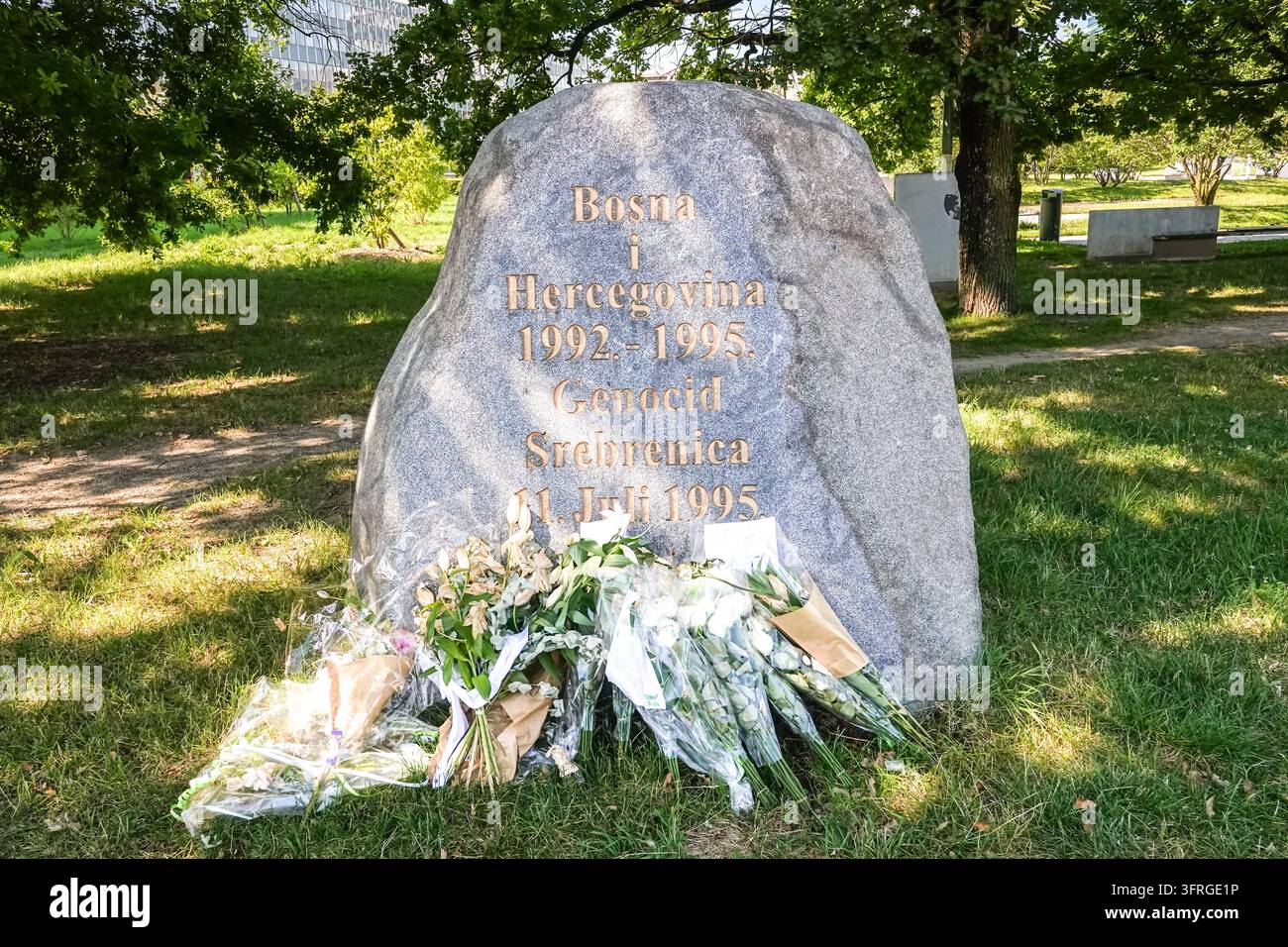 Fiori giacciono ai piedi di una pietra con l'iscrizione "Bosna i Hercegovina 1992 - 1995, Genocid Srebrenica, 11. Juli 1995", che commemora il genocidio di Srebrenica, a Ginevra, Svizzera, il 20 luglio 2024, giorni dopo il 29° anniversario del massacro di luglio 1995 di più di 8.000 uomini e ragazzi bosniaci. Foto Stock