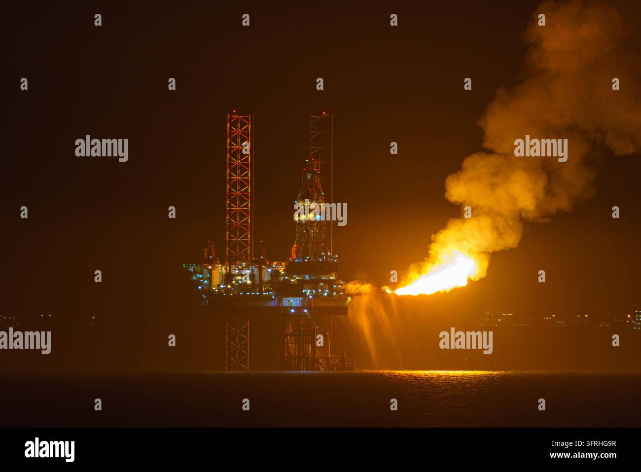 Doha, Qatar - 14 gen 2024, Vista panoramica della piattaforma petrolifera, che brucia il gas naturale in eccesso, durante la produzione di petrolio, nel Golfo Persico, di notte, Doha, Qatar Foto Stock