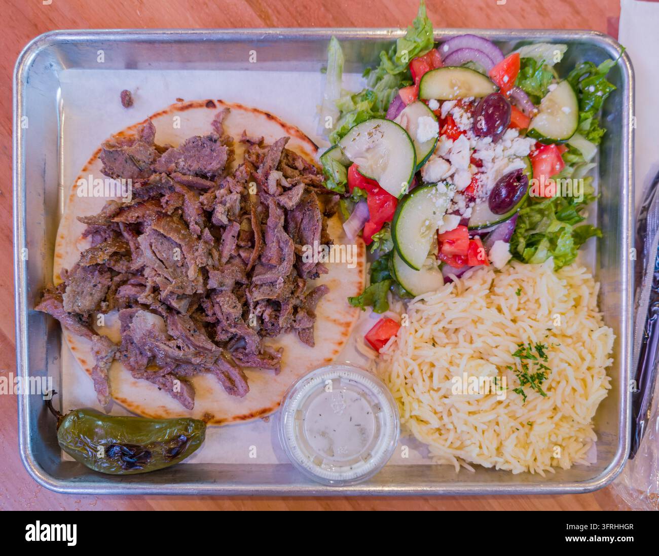 Una vista dall'alto di un vassoio di metallo contenente un gyro con carne sfilacciata, un'insalata greca con feta e olive, riso condito e un peperone arrosto Foto Stock