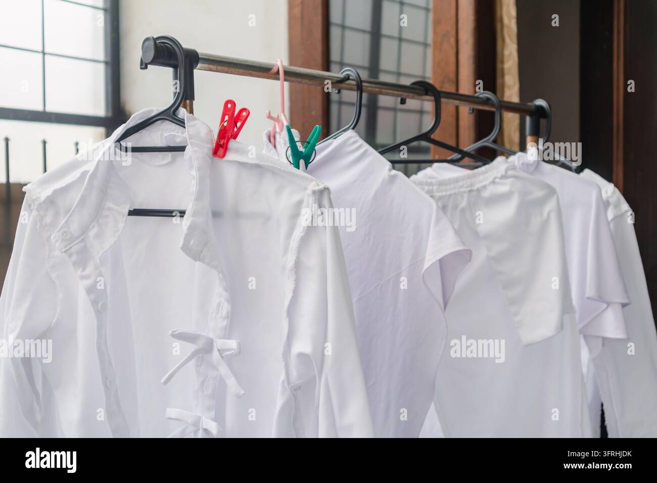 Un appendiabiti con diversi capi bianchi appesi a grucce di plastica nera. Bianchi appena lavati. Foto Stock