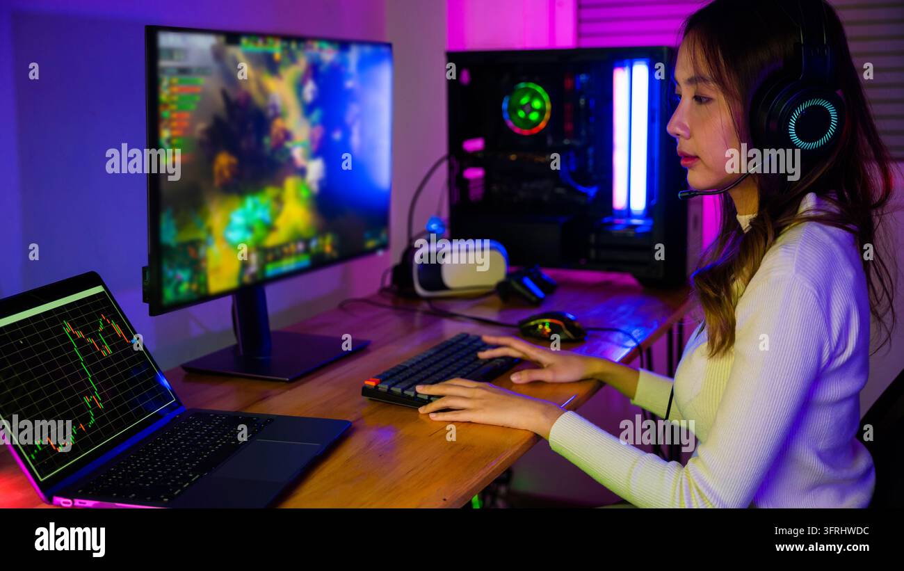 Giocatore professionista asiatico che gioca a un videogioco online sullo schermo del computer fisso PC con luci LED al neon colorate, giovane donna con cuffie da gaming Foto Stock