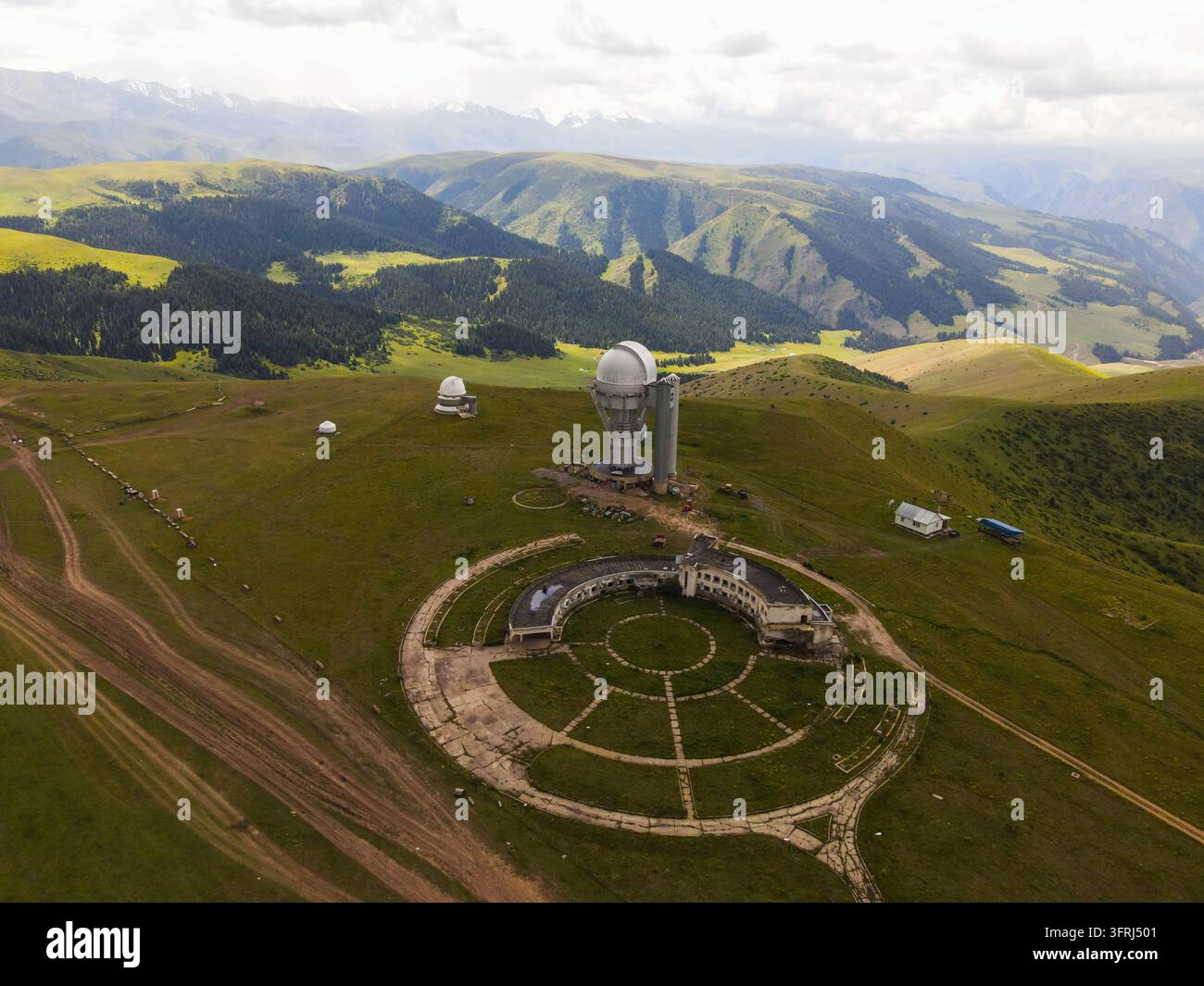 Vista elevata del cupolino del telescopio dell'osservatorio Assy-Turgen e di una struttura circolare su una cresta erbosa dell'altopiano di Assy Foto Stock
