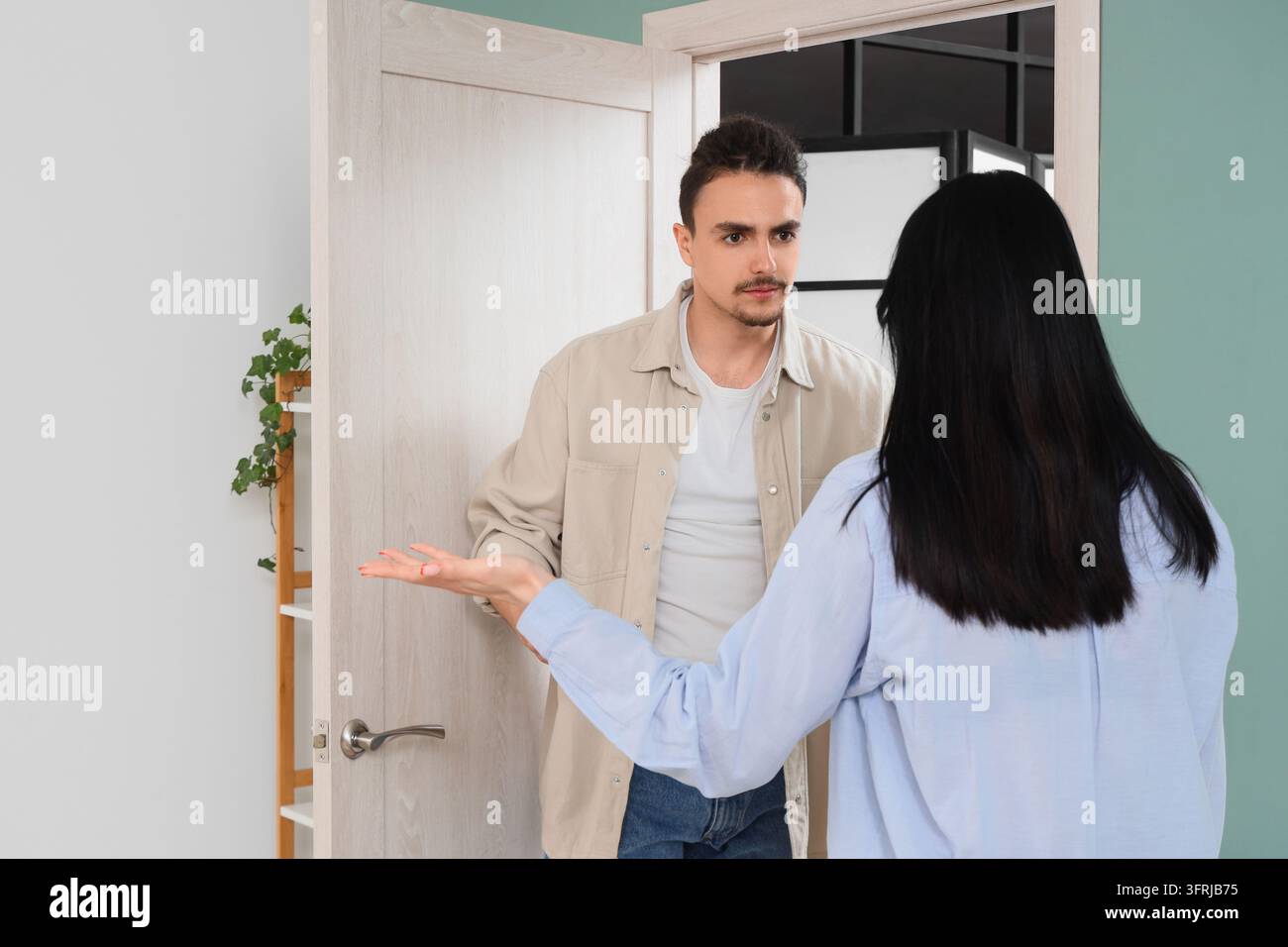 Conflitto relazionale e rottura della comunicazione, coppia che litiga a casa con uomo e donna che hanno una discussione tesa in una porta Foto Stock