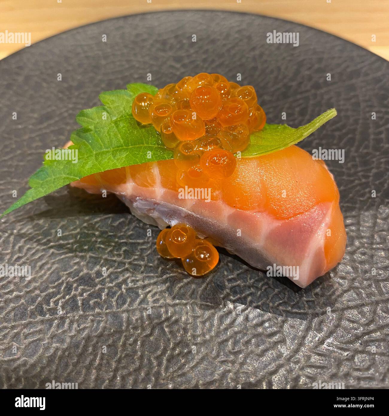 Sushi nigiri al salmone guarnito con uova di salmone ikura e una foglia fresca di shiso a Hakata, Fukuoka, Giappone. Foto Stock