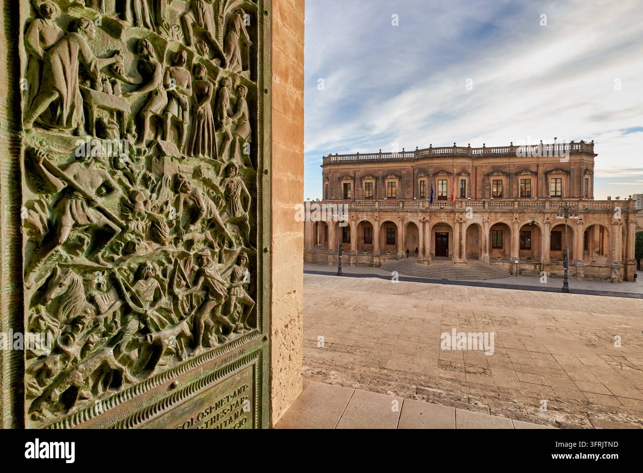 Palazzo comunale del XVIII secolo con loggia ad arcate, incorniciato da una porta in bronzo a rilievo della Cattedrale di San Nicolo a Noto, in Italia, in un pomeriggio invernale Foto Stock