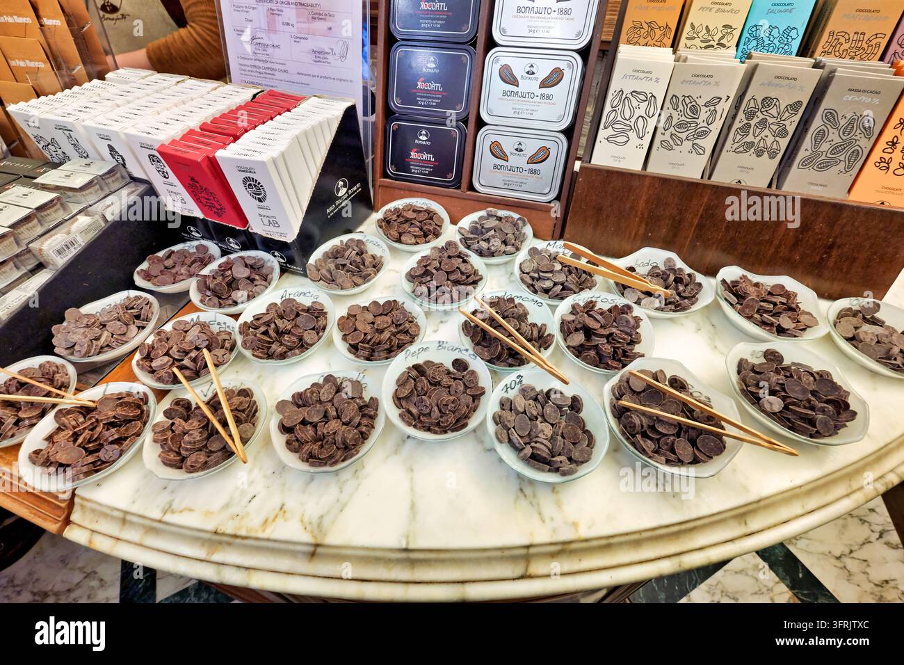 Ciotole di dischi di cacao aromatizzati con pinze di legno su un bancone di marmo all'Antica Dolceria Bonajuto, una storica pasticceria in Sicilia, Italia Foto Stock