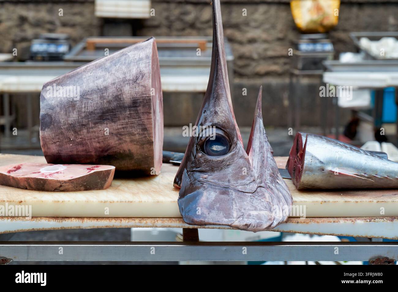 Testa di pesce spada mozzata, filetto tagliato e bistecca cruda su un tagliere in una bancarella di pesci a Catania, Sicilia, Italia Foto Stock