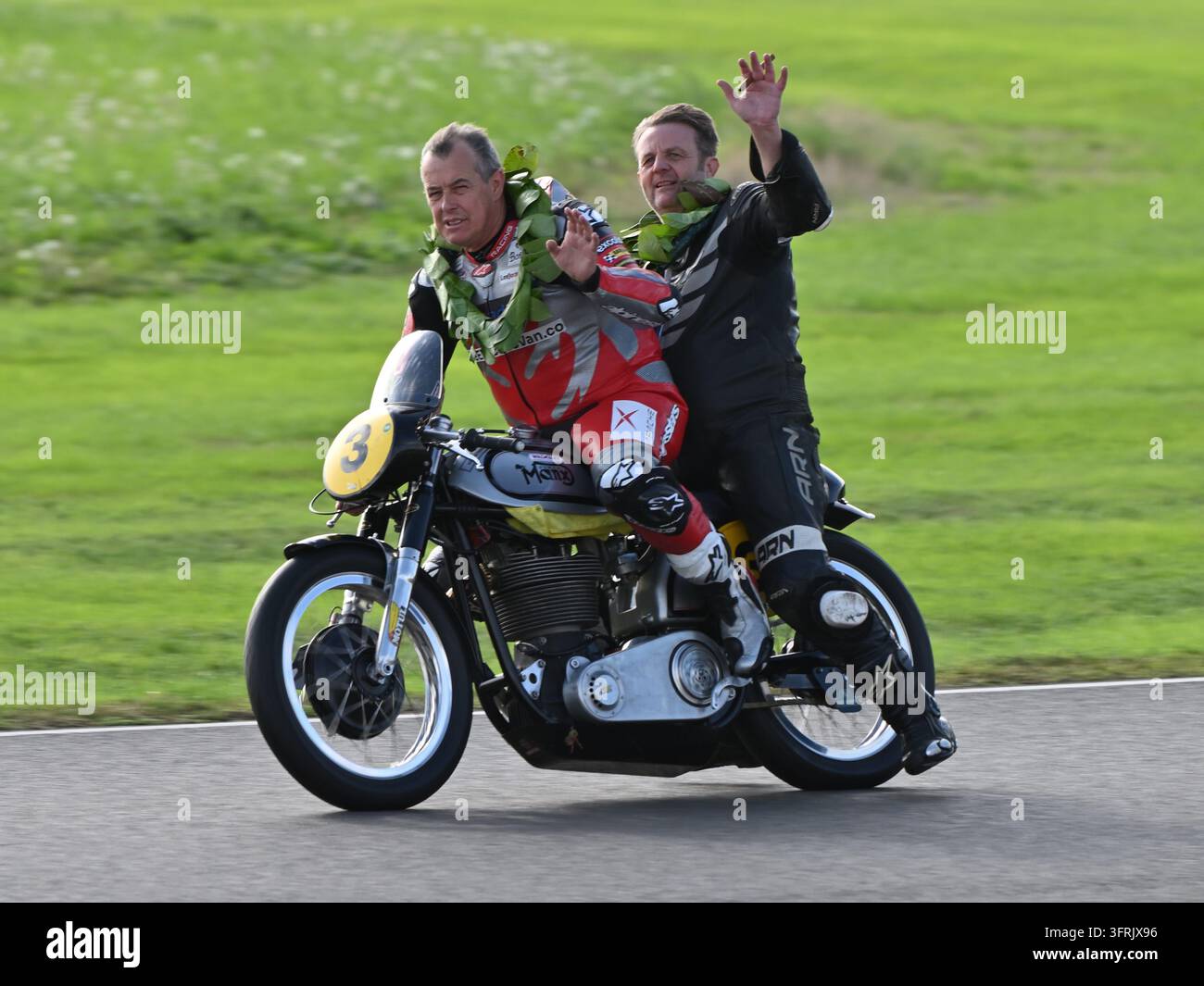 John McGuinness e il compagno di squadra Richard Parker al Goodwood Revival 2026 - giro di vittoria sulla Norton Manx Foto Stock