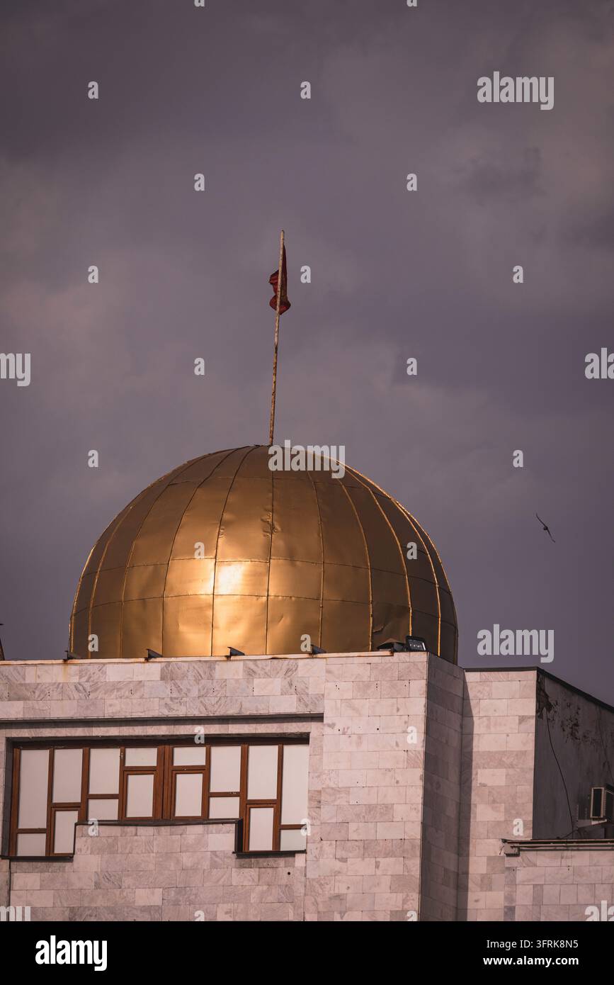 Una cupola dorata su un edificio di marmo sotto nuvole tempestose Foto Stock