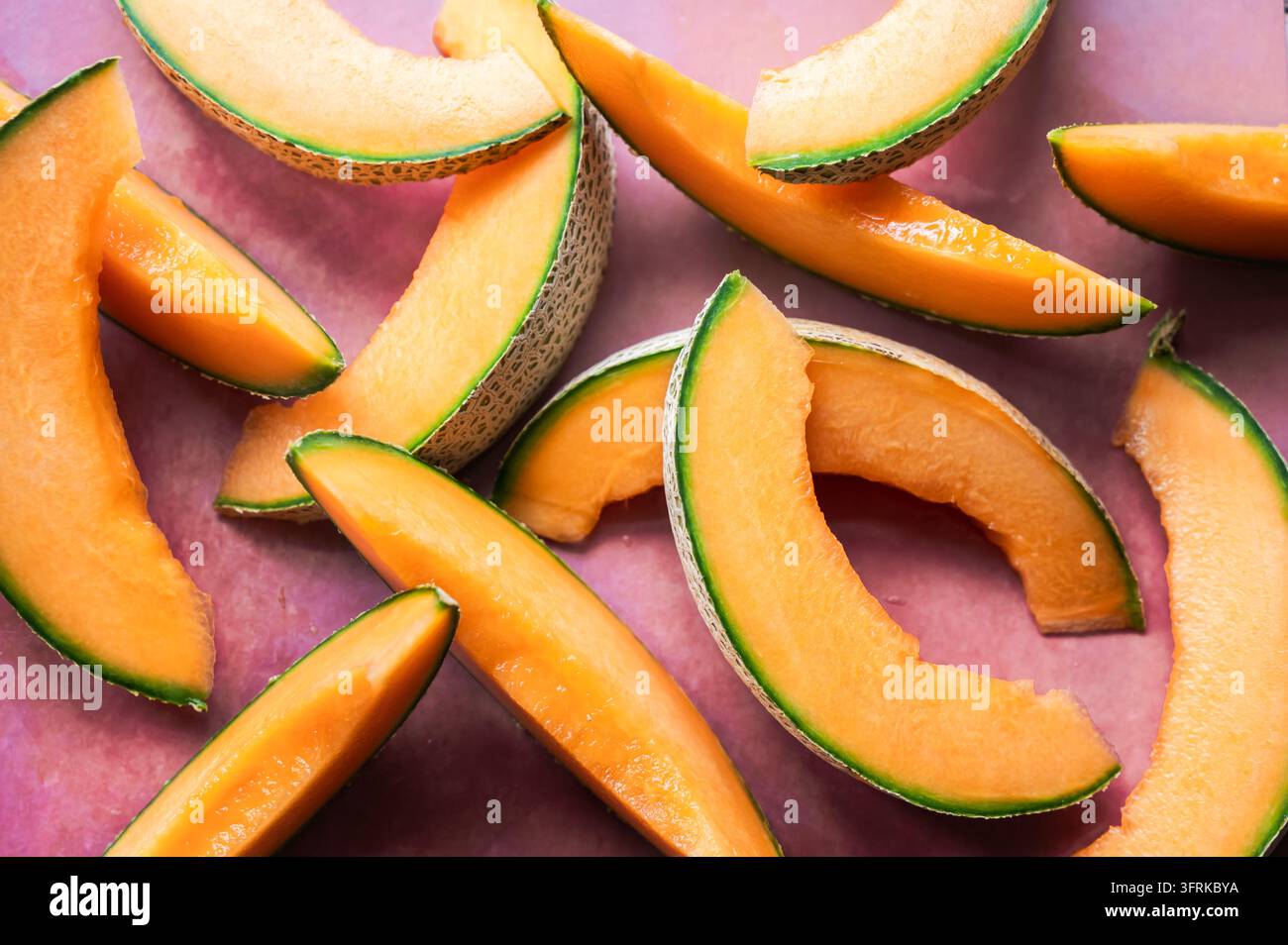 Fette fette di melone cantalupo su uno sfondo rosa viste dall'alto Foto Stock