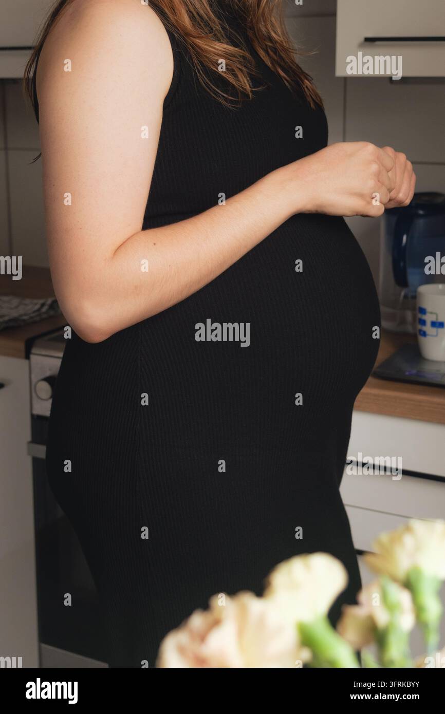 Una donna incinta che prepara il caffè in cucina Foto Stock