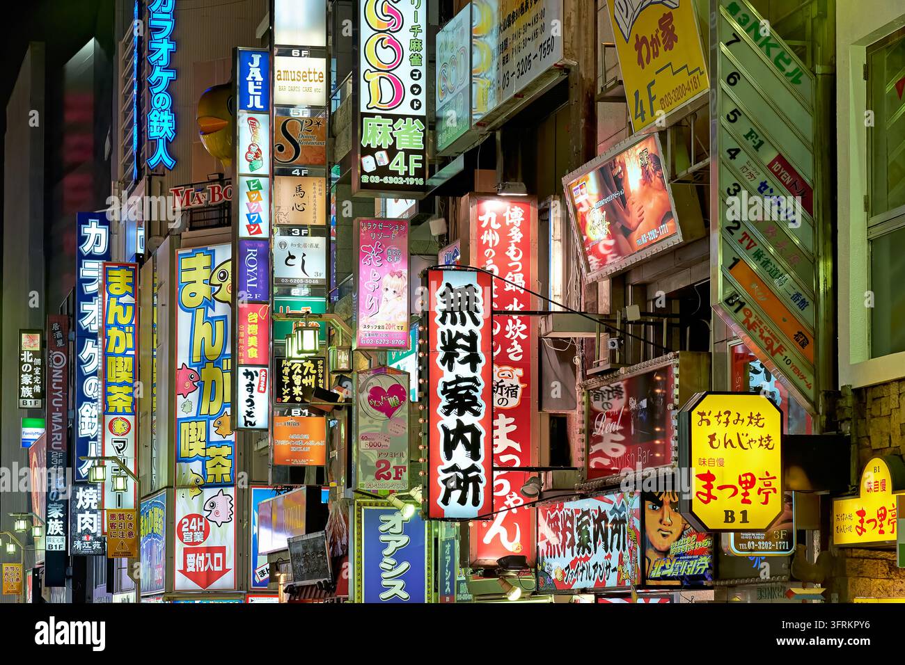Fitta agglomerazione di cartelli giapponesi illuminati che pubblicizzano karaoke, caffè manga, sale mahjong e ristoranti su una strada della vita notturna a Tokyo. Foto Stock
