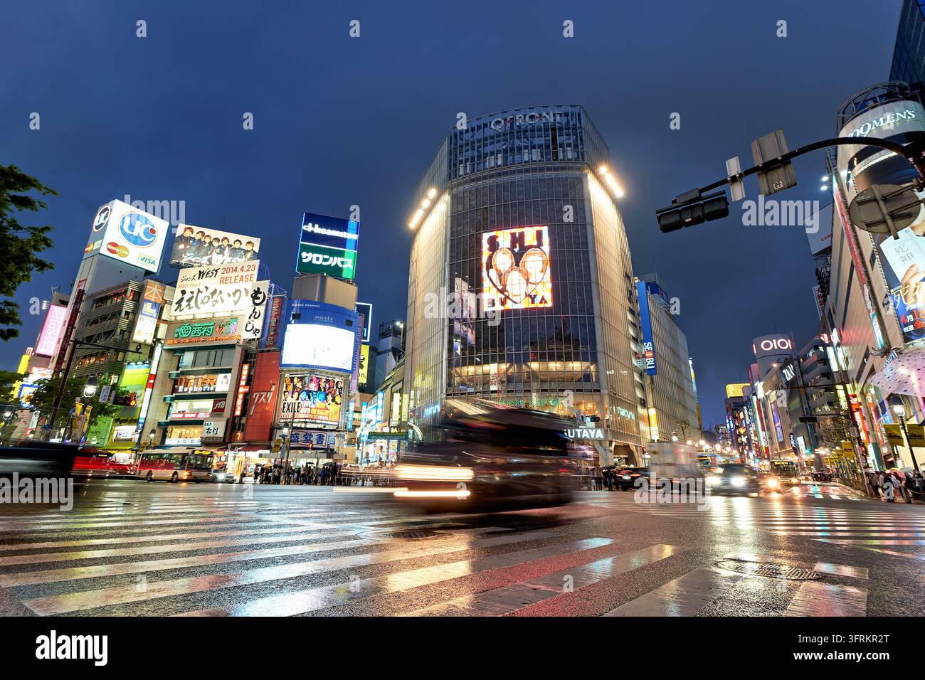 Passaggio pedonale bagnato e confuso e cartelloni pubblicitari illuminati a Shibuya, Tokyo, Giappone, con scie di luce delle auto durante una serata piovosa di primavera nell'aprile 2014. Foto Stock