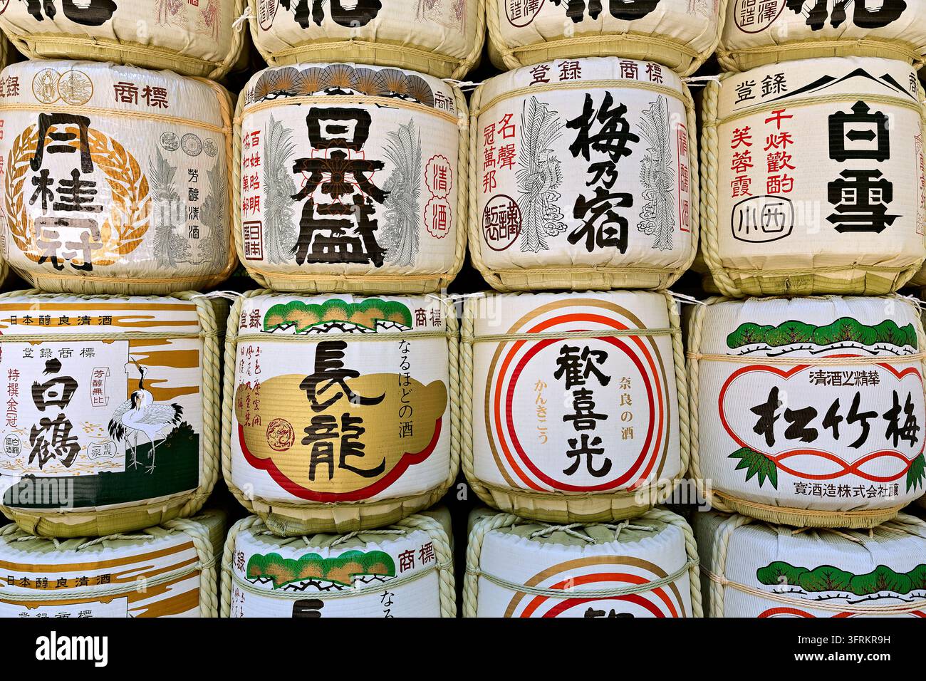 Kazaridaru, botti di vino di riso avvolti in paglia con etichette kanji dipinte e motivi di gru e pini, disposti in file in Giappone Foto Stock